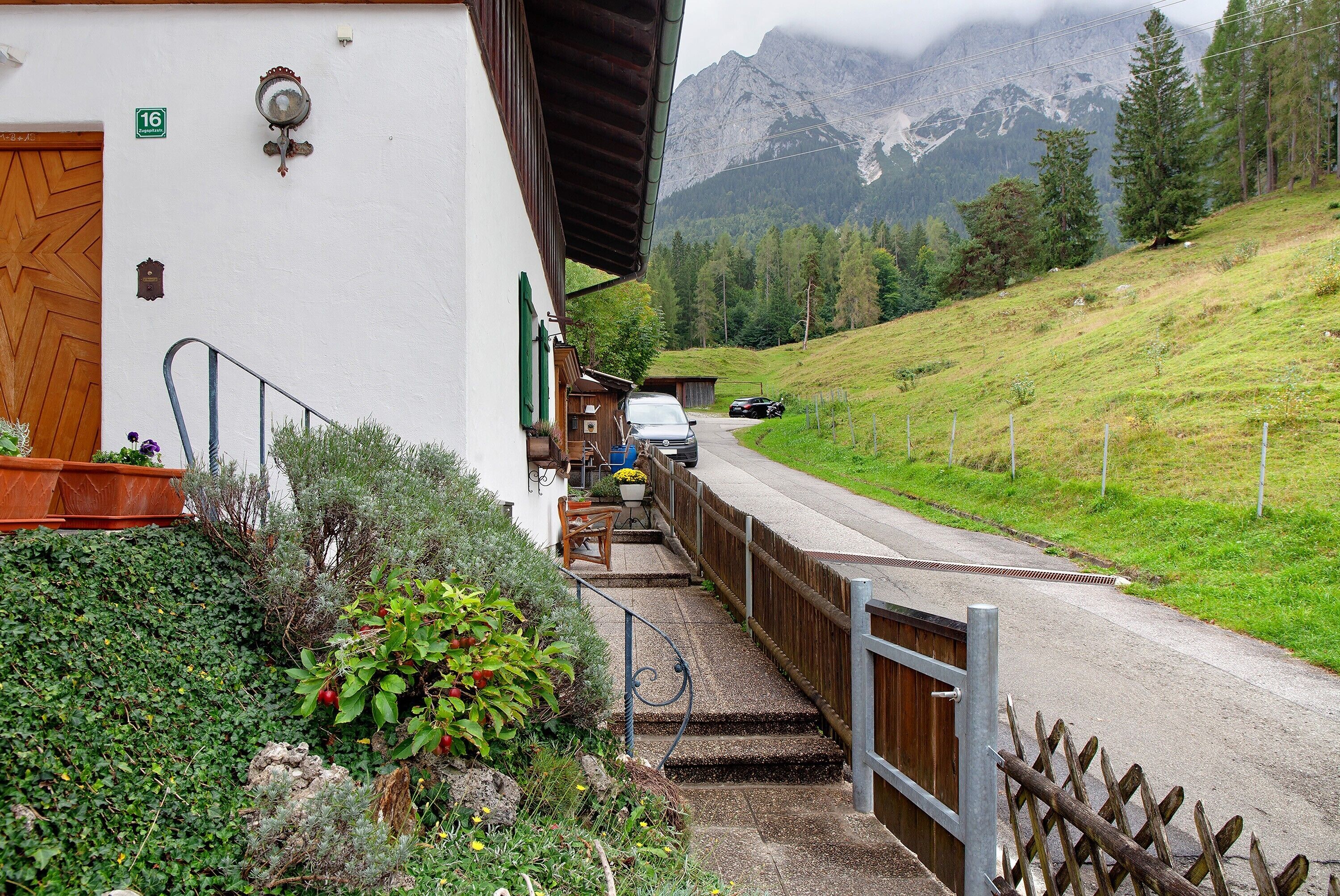 Ein Gebäude mit einer Holztür, einer Treppe, die zu einer Veranda führt, und Blick auf einen Berg.