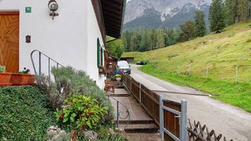 Ein Gebäude mit einer Holztür, einer Treppe, die zu einer Veranda führt, und Blick auf einen Berg.