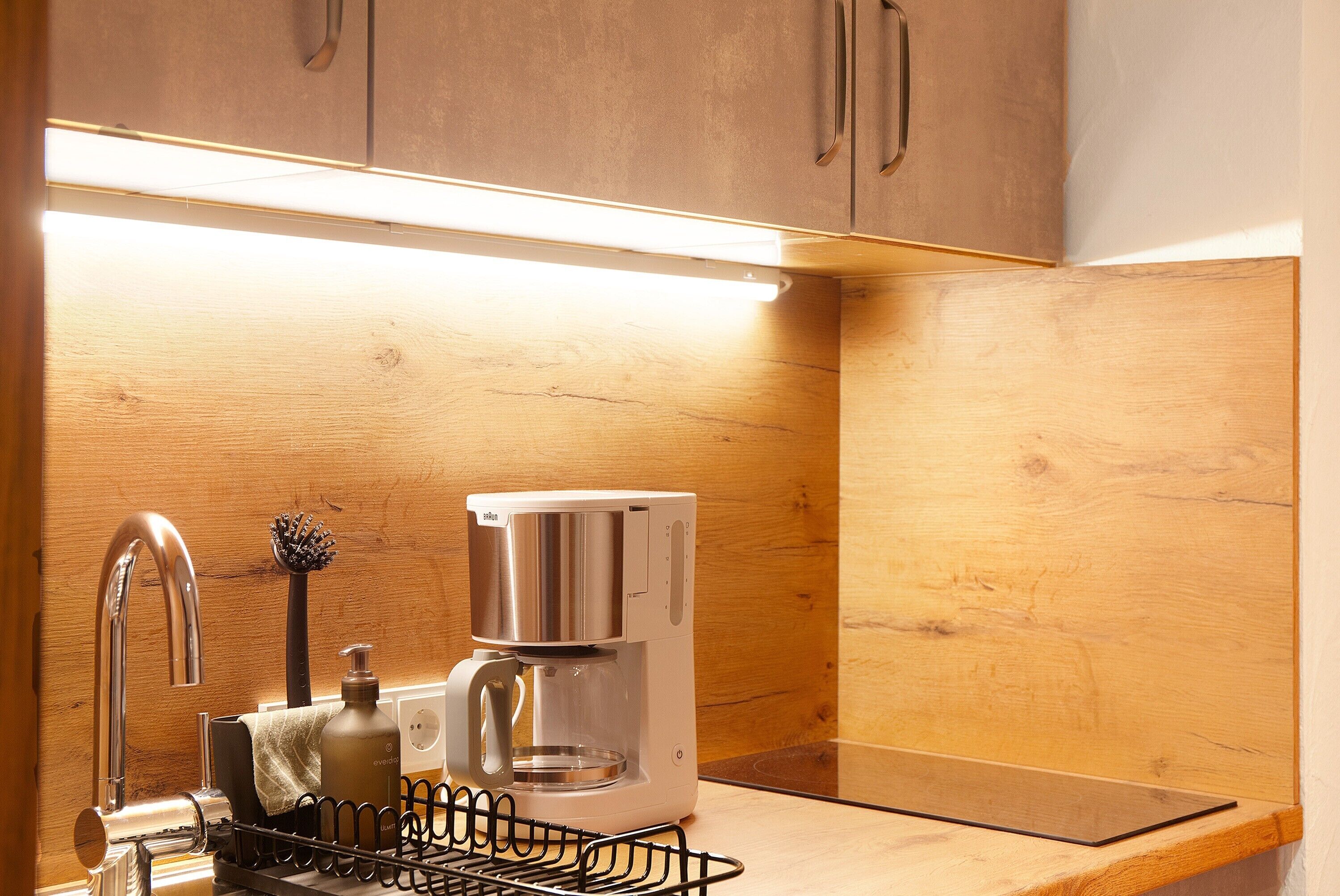 Une cuisine équipée d’une machine à café, d’un évier et d’un plan de travail en bois.