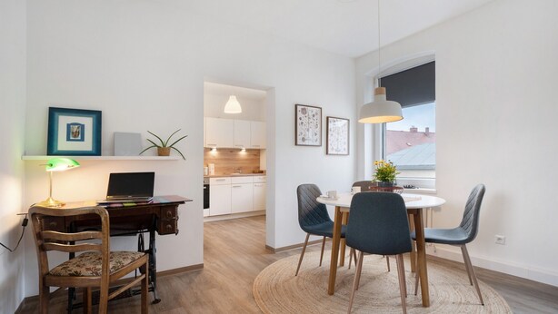 A modern apartment with a wooden desk, a dining table with chairs, a laptop, and framed pictures on the walls. - Holiday Apartment "Finsterwalde" (FInsterwalde)