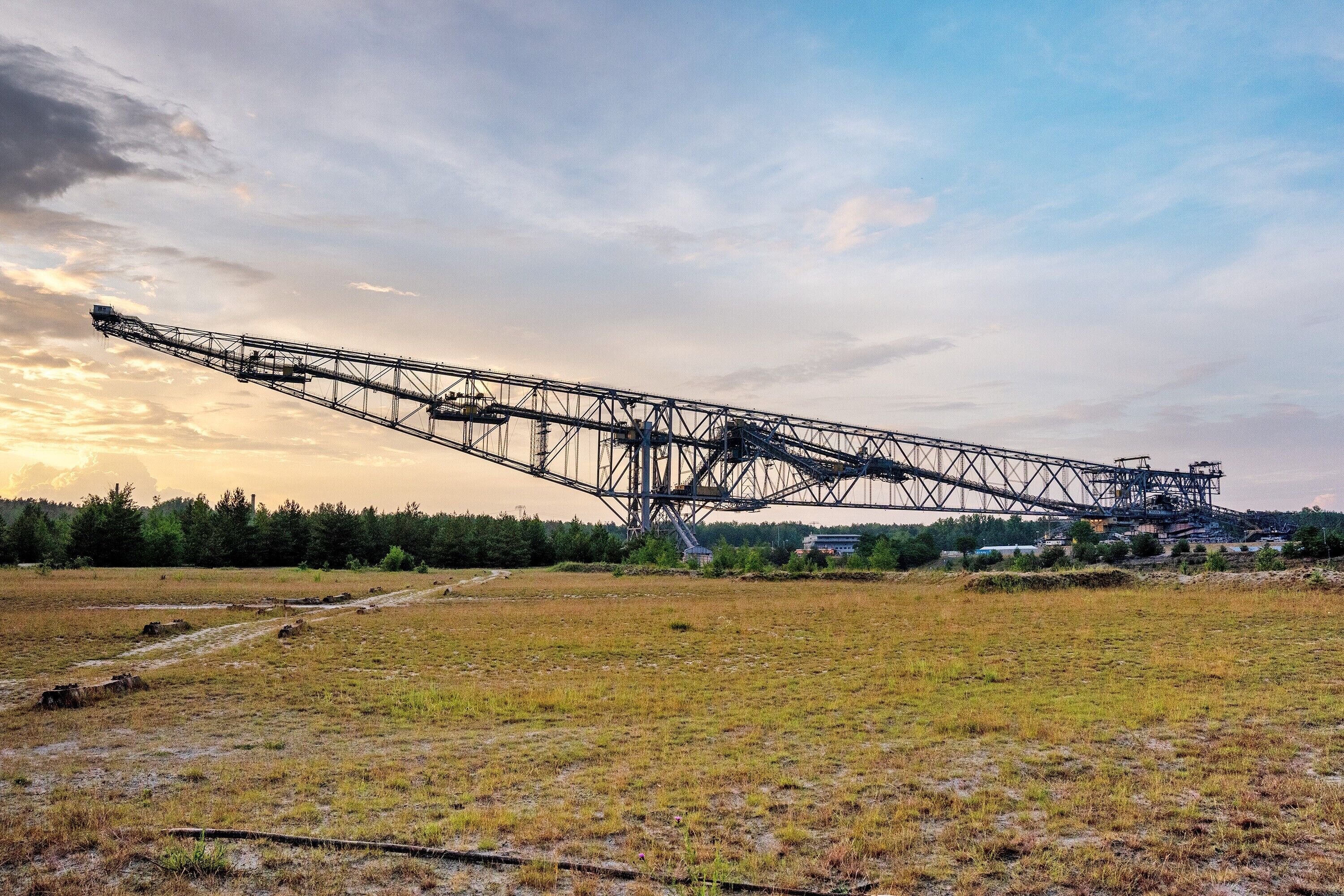 Une grande grue industrielle se dresse dans un champ dégagé, sous un ciel clair.