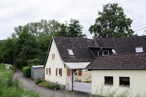 Ett hus på landsbygden med ett sluttande tak, en liten veranda och ett vitt staket.