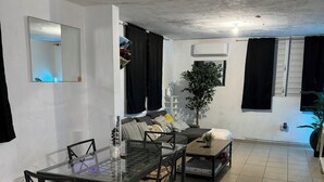 A dining area with a glass-top table, black chairs, and a potted plant.