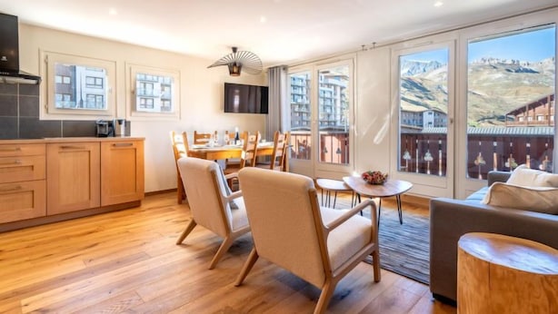 Un amplio salón con mesa de comedor, asientos cómodos, un sofá y grandes ventanales con vistas a la montaña.