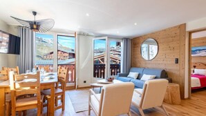 Una sala de estar moderna con piso de madera, un espejo redondo, un sofá y un comedor con muebles de madera.