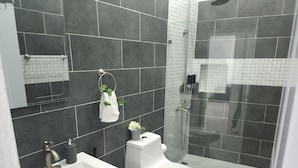 Une salle de bain moderne avec un lavabo, des toilettes et une douche, le tout de couleur blanche.
