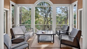 Un patio techado con mobiliario de mimbre, una mesa y un ventilador de techo.