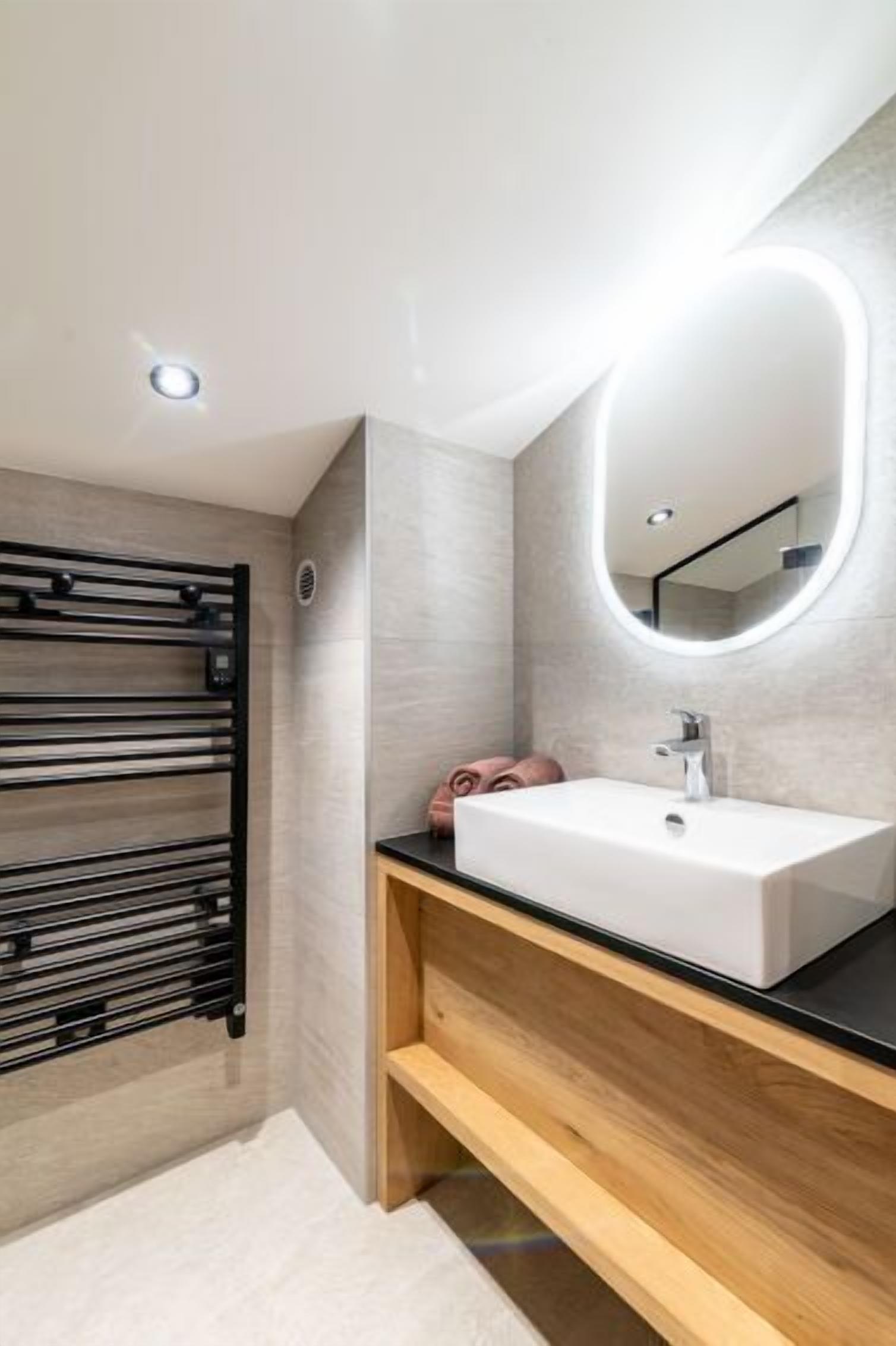 A modern bathroom with a white sink, wooden vanity, and a towel rack.