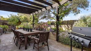 Relax in the serene outdoor patio, complete with a barbecue grill and comfortable seating under a shaded pergola.
