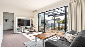 Relax in this cozy living space with a large flat-screen TV, comfortable sofa, and sliding door to a balcony.