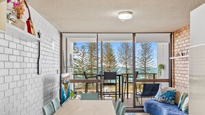 A modern interior with a dining area, a sofa, and a view of trees through large glass doors.