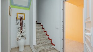A staircase with red steps leading to a door, a white vase with flowers on the floor, and a framed picture on the wall. - Apartment 'Relax' with Shared Garden, Balcony and Wi-Fi (Ciudadela de Menorca)