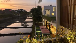 A modern building with a balcony overlooking a water feature. - Mandala Clubhouse (Canggu)