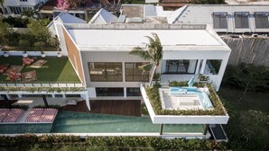 A modern house with a swimming pool, a covered patio, and a lush garden. - Mandala Clubhouse (Canggu)