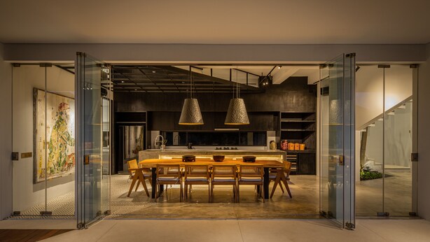 A modern kitchen with a dining area, featuring a large table and chairs, pendant lighting, and a view into the adjacent living space. - Mandala Clubhouse (Canggu)