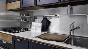 A modern kitchen with a stainless steel sink, a wooden cutting board, and a stainless steel range hood. - Italianway Comfort - Torino 48 (Milan)