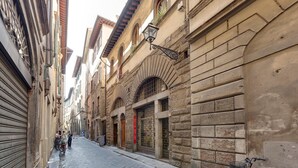 Une rue étroite bordée de bâtiments historiques, avec un volet fermé sur la gauche et un vélo sur la droite.