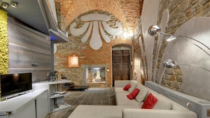 Un salon moderne avec un mur en pierre, une cheminée, un canapé et un téléviseur.