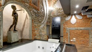 Une salle de bain moderne avec un mur en pierre, une baignoire sur pieds et une statue.