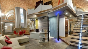 Un salon moderne avec un mur en pierre, une cheminée et un escalier.