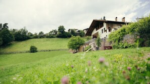 Ein Haus mit geneigtem Dach, einem Holzzaun und einer grünen Wiese.