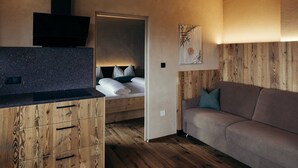 Ein kleines Zimmer mit einem Bett, einer Couch, einem Fernseher und einem Holzkasten.