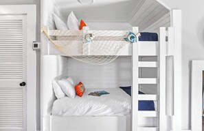 Uma cama beliche com dossel de rede, roupa de cama branca e escada.
