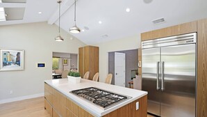 A modern kitchen with a central island, stainless steel appliances, and wooden cabinetry. - Huge Secluded Cowan Heights Home, Pool, Entertainers Delight (4 beds/5 baths) (Santa Ana)
