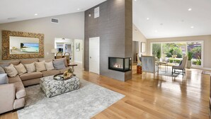 A spacious living room with a fireplace, a large mirror, and a view of the outdoors. - Huge Secluded Cowan Heights Home, Pool, Entertainers Delight (4 beds/5 baths) (Santa Ana)