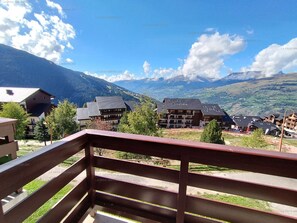 Bergblick mit Gebäuden im Vordergrund und blauem Himmel.