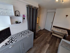 A compact living space with a kitchenette, a small seating area, and a door leading to another room. - Paradiski closed to the slopes vallandry (LANDRY)