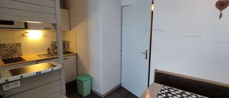 A compact kitchen with a sink, a small trash bin, and a table with a decorative item.