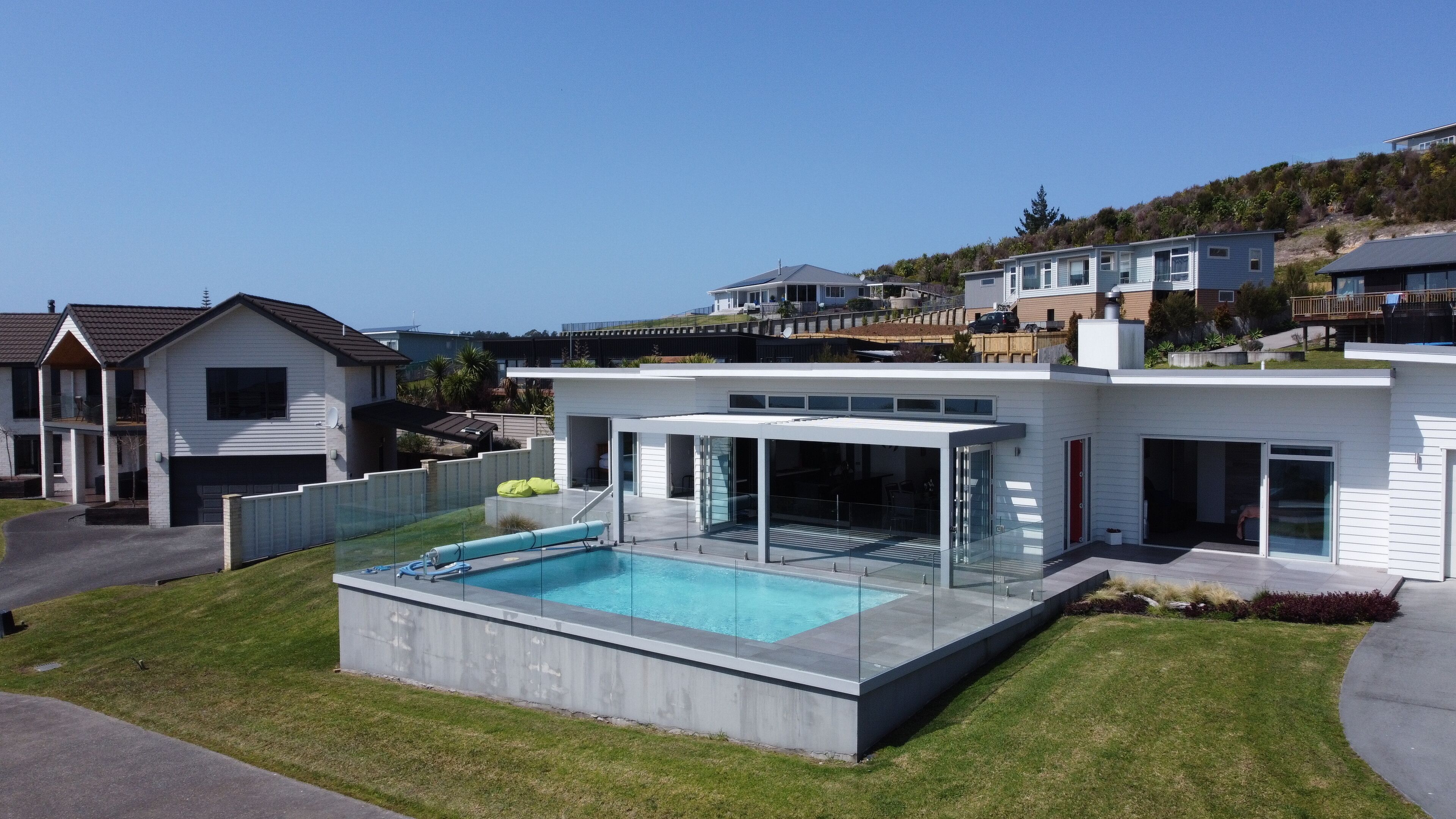 Una moderna casa a due piani con una grande area piscina vetrata e un patio coperto.