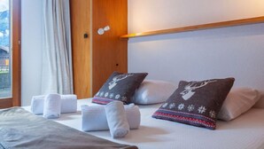 Een hotelkamer met een bed, twee kussens met hertenmotieven, een plaid en handdoeken.
