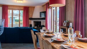 Een gezellige woonkamer met een blauwe bank, een houten eettafel gedekt voor een maaltijd en een open haard.