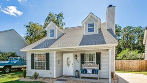 A single-story house with a front porch, a chimney, and a small garden area.