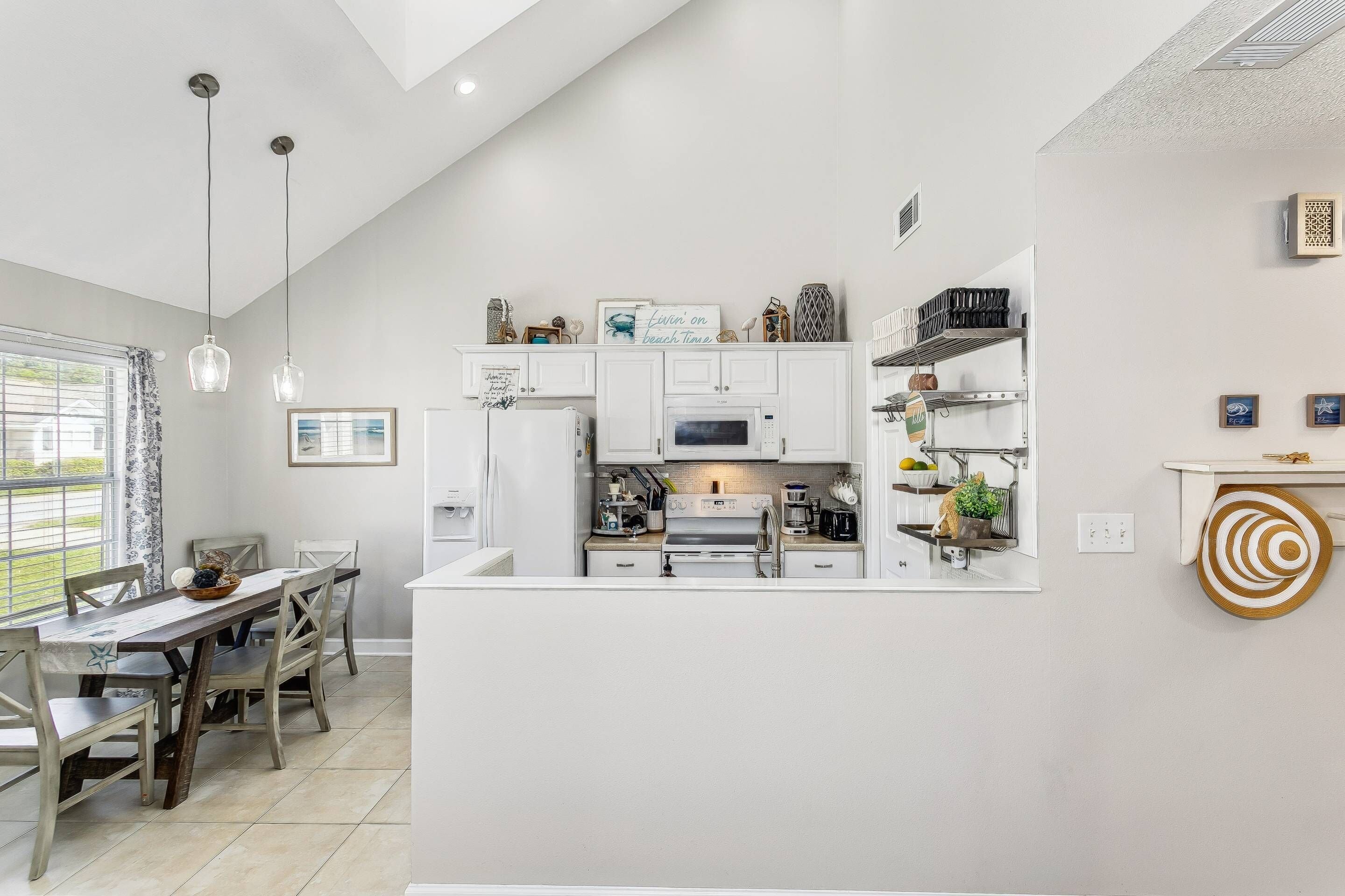A modern kitchen with white cabinetry, a central island, and pendant lighting.