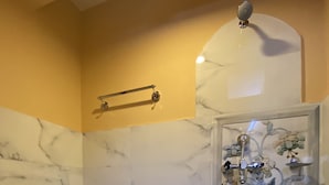 Un baño con inodoro, ducha y pared de mármol.