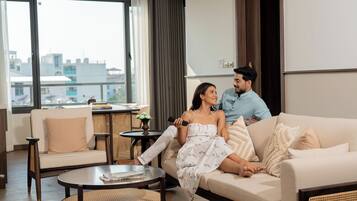 A modern living room with a sofa, a round coffee table, and a view of the city through large windows.