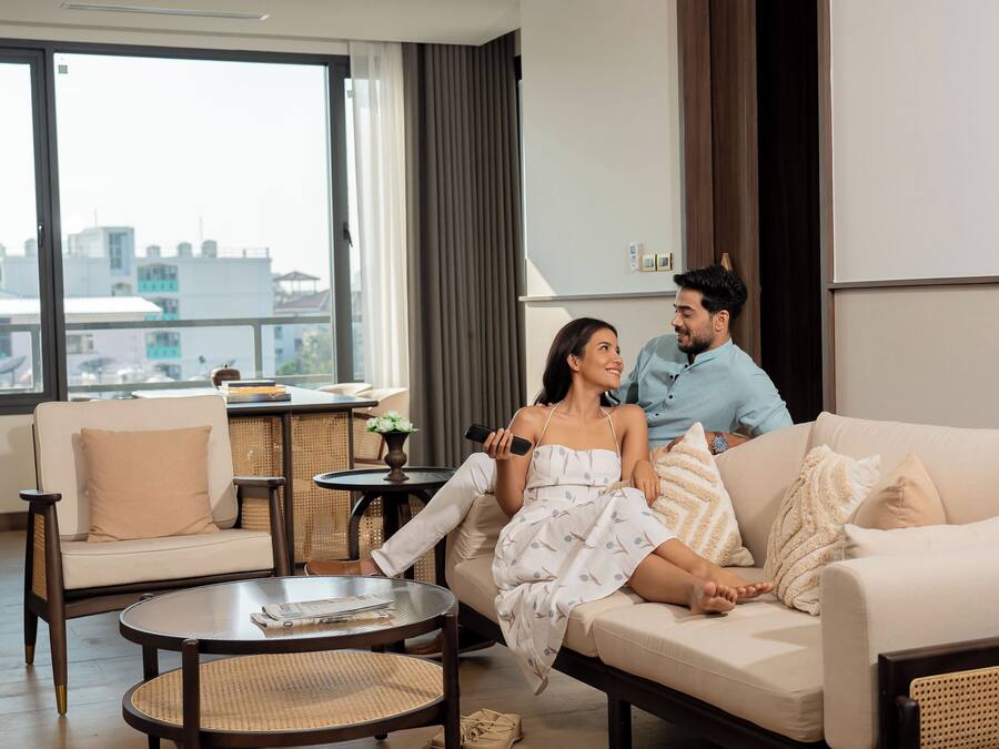 A modern living room with a sofa, a round coffee table, and a view of the city through large windows.