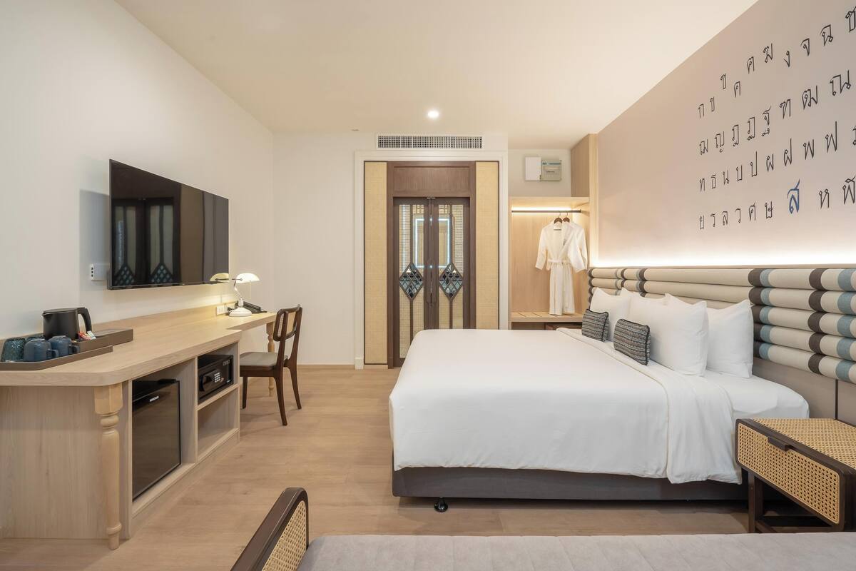 Habitació d'hotel amb llit, taulell de nit, cadira, escriptori i armari.