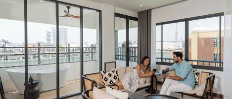 Una sala de estar moderna con una bañera grande, muebles de mimbre y ventanas amplias que dan a vistas de la ciudad.