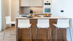 A modern kitchen with a central island, white bar stools, and built-in appliances. - 2-BD Luxury Apt  Sea View Balcony near the beach (Voula)