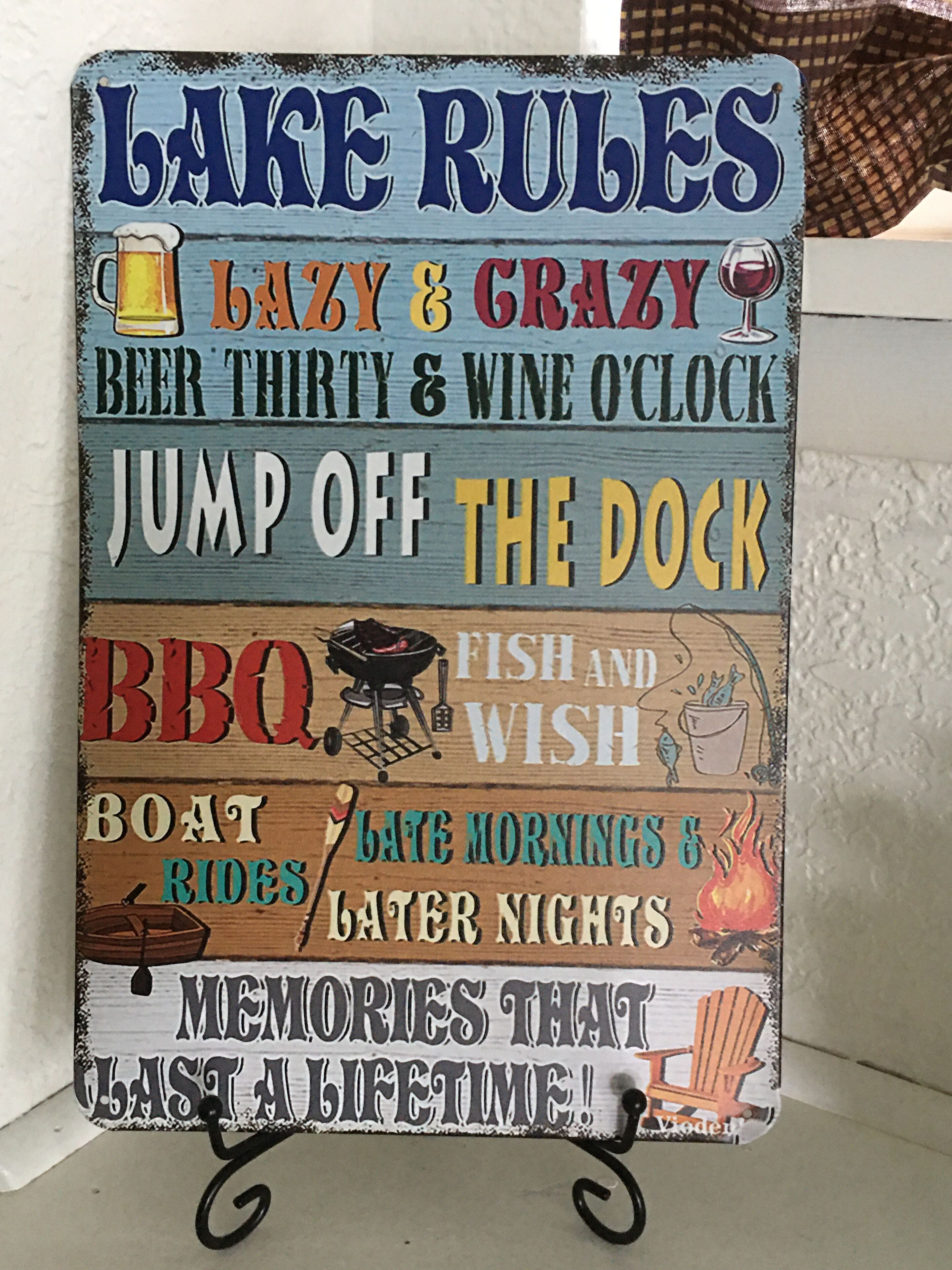 Ein Schild mit verschiedenen Sprüchen wie 'LAZY & CRAZY', 'BEER THIRTY & WINE O'CLOCK' und 'JUMP OFF THE DOCK', das eine entspannte und lustige Atmosphäre vermittelt.