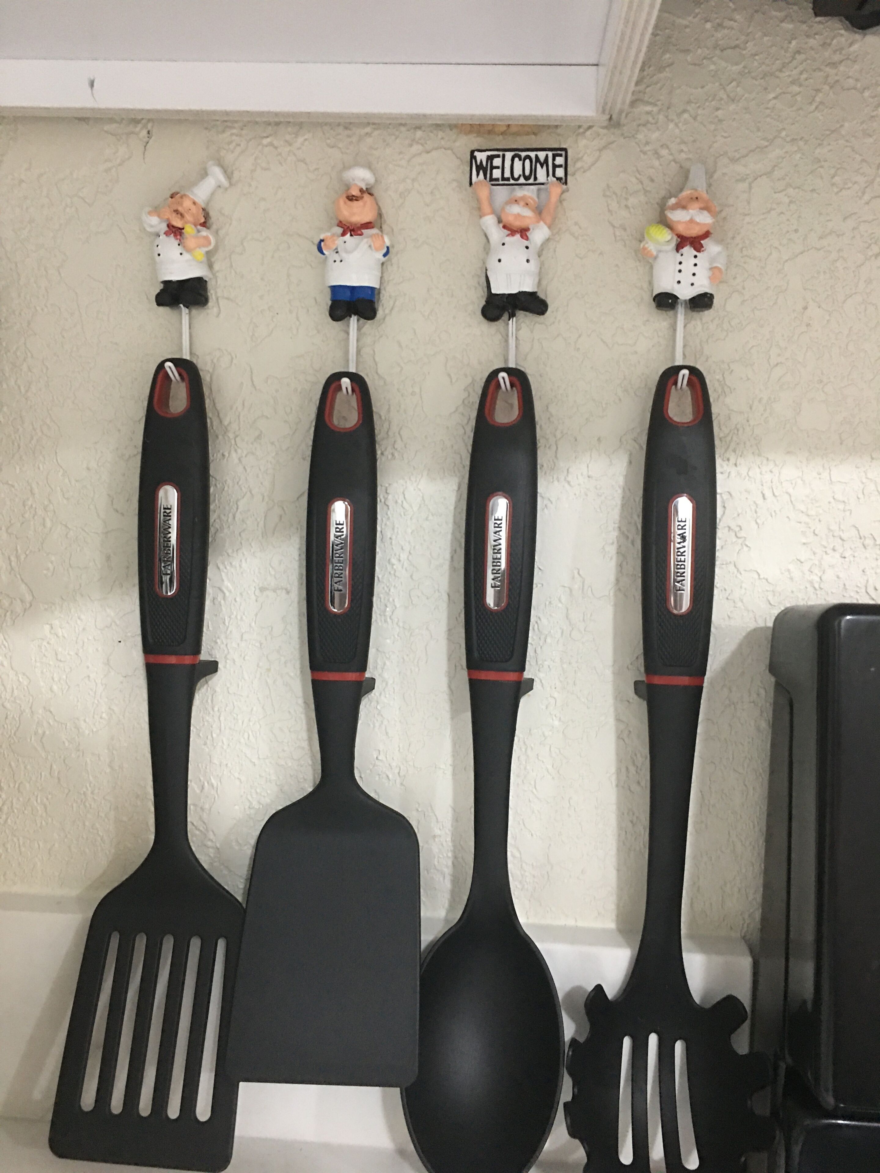 Kitchen utensils hanging on a wall, including spatulas and a ladle.