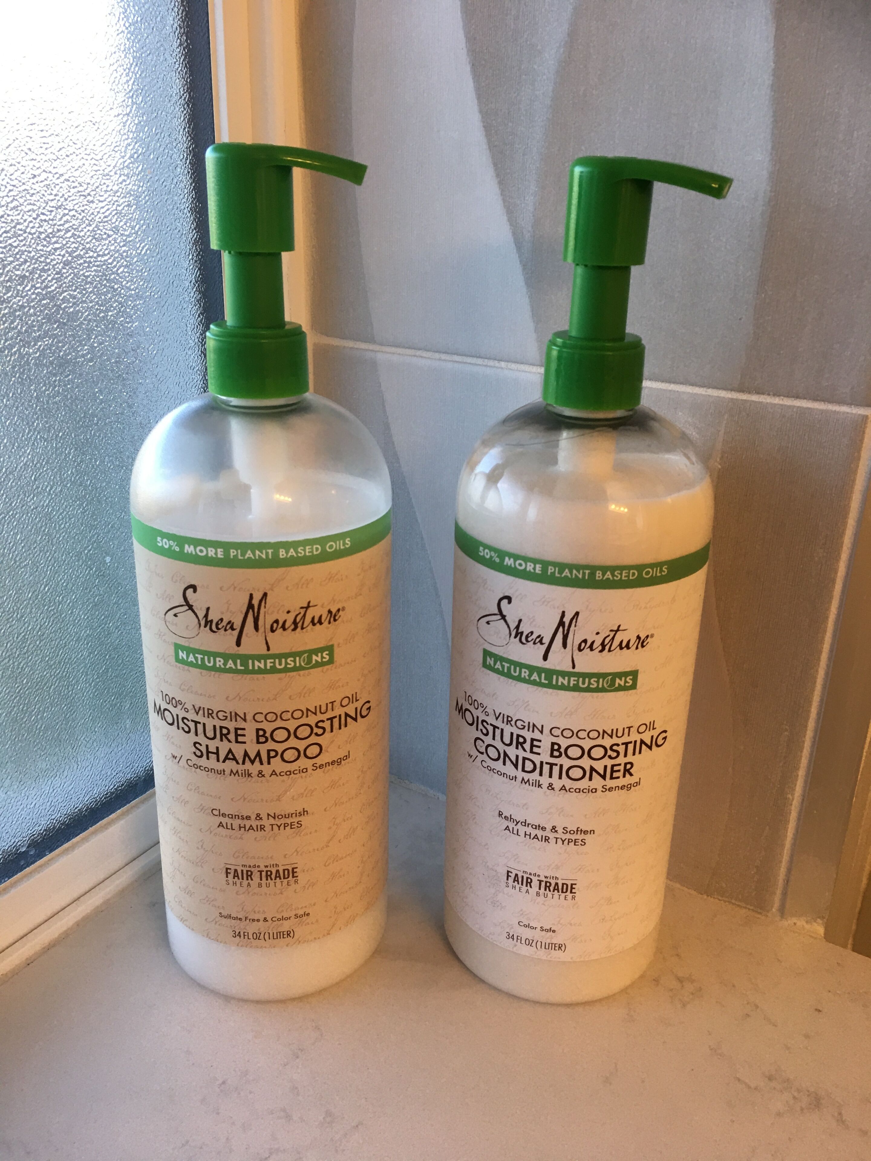 Two bottles of Shea Moisture natural infusions shampoo and conditioner on a bathroom counter.