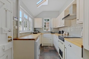 A kitchen with white cabinets, a wooden countertop, a built-in oven, and a window with a view of the outside.