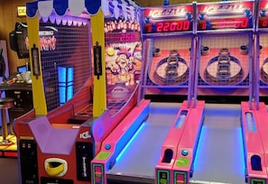 An arcade with various gaming machines, including a claw machine and a racing game.