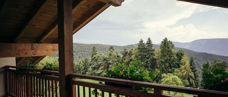 Ein hölzerner Balkon mit Blick auf eine bewaldete Berglandschaft.