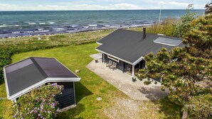 Une maison située sur la côte, dotée d’une grande terrasse, d’un espace salon extérieur abrité et offrant une vue sur l’océan.